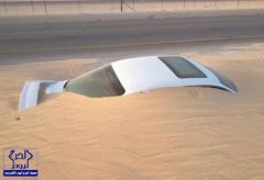 بالصور.. زحف الرمال يخفي سيارة مركونة على جانب طريق الدمام